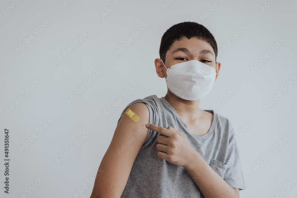 Asian boy showing shoulders after getting a vaccine. Happy little boy showing arm with band-aids on after vaccine injection. Asian boy showing shoulders after getting a vaccine. Happy little boy showing arm with band-aids on after vaccine injection.