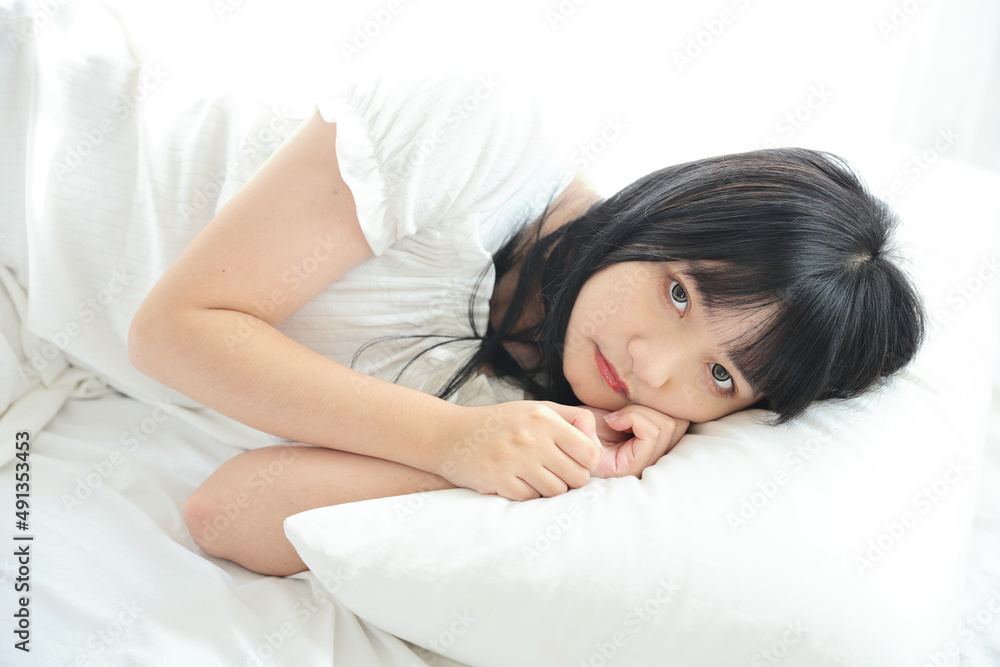 Beautiful young Asian woman sleeping on bed relaxing in the morning light with white room Beautiful young Asian woman sleeping on bed relaxing in the morning light with white room