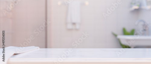 Empty white marble bathroom countertop over blurred white bathroom background.