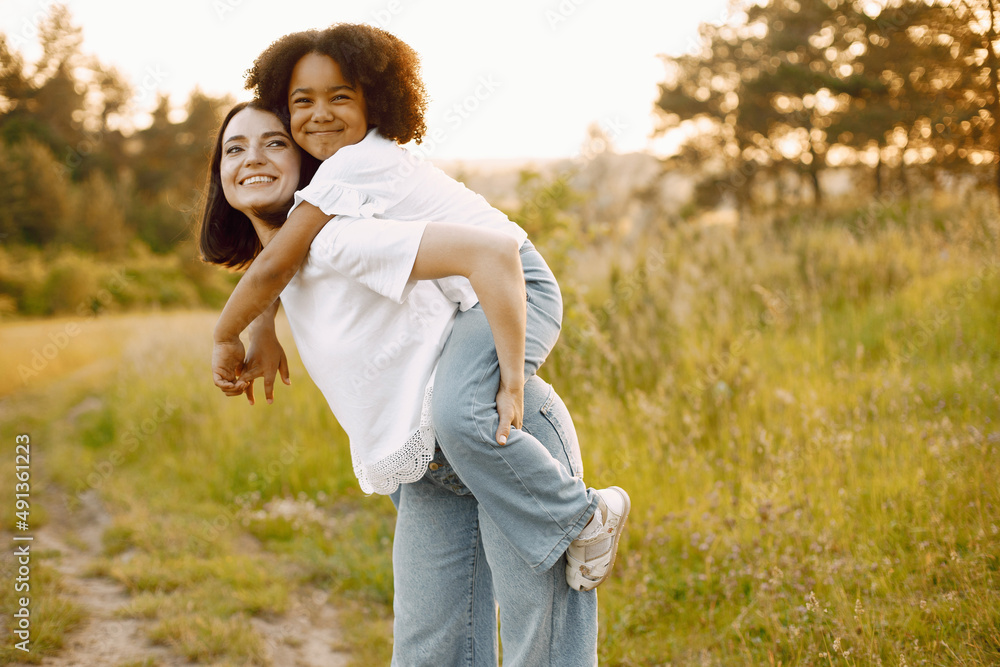 Fototapeta premium Caucasian mother holding her mixed race daughter on her back