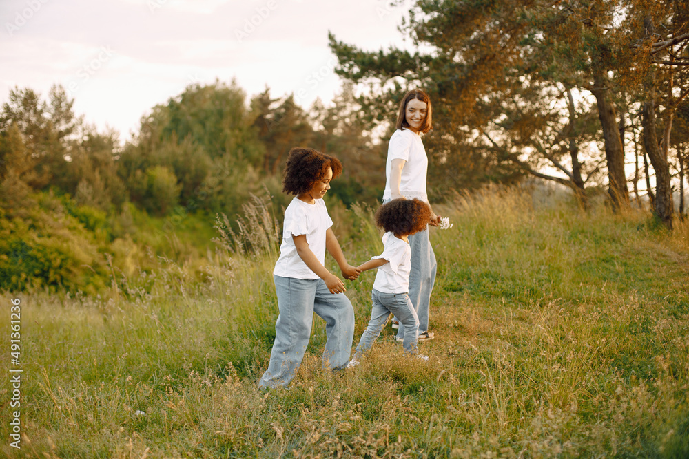 Caucasian mother and two her mixed race daughters walking in a park Caucasian mother and two her mixed race daughters walking in a park