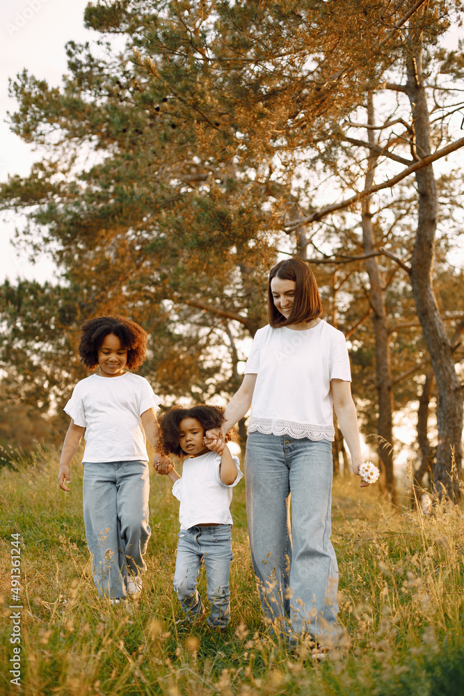Fototapeta premium Caucasian mother and two her mixed race daughters walking in a park