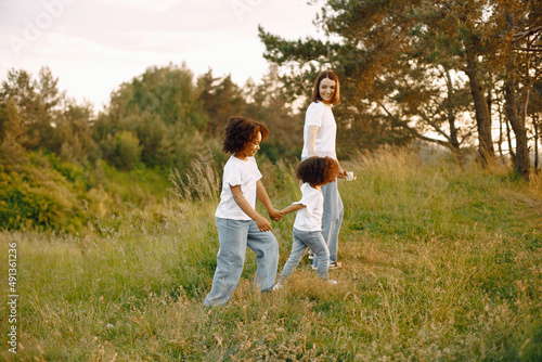 Caucasian mother and two her mixed race daughters walking in a park © prostooleh