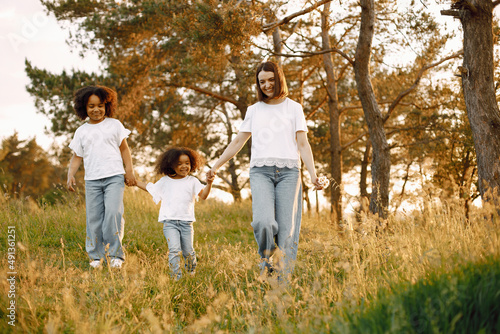 Caucasian mother and two her mixed race daughters walking in a park