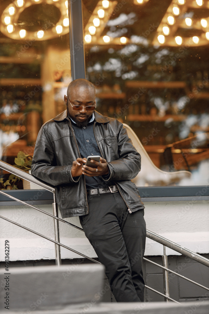 Black man standing on a street and using a phone Black man standing on a street and using a phone