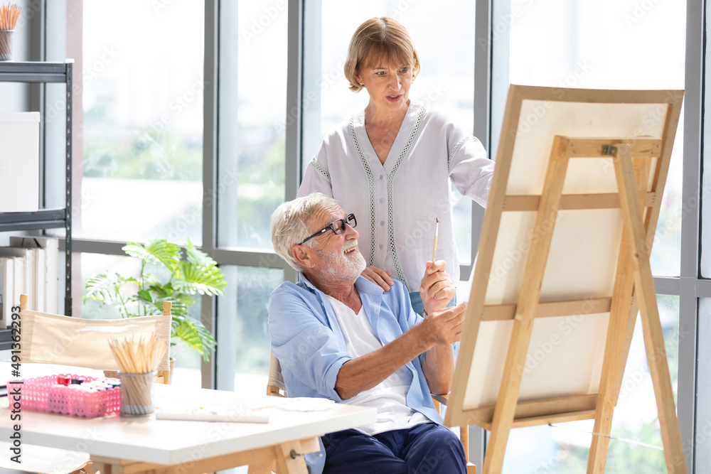senior couple artist talking about painting work in office