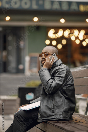 Black man sitting on a bench and using a phone
