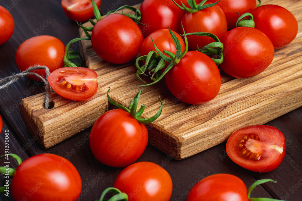 Red tomato in glass bowl on cutting board on wooden table. Organic healthy food. Cooking Ingredients Red tomato in glass bowl on cutting board on wooden table. Organic healthy food. Cooking Ingredients