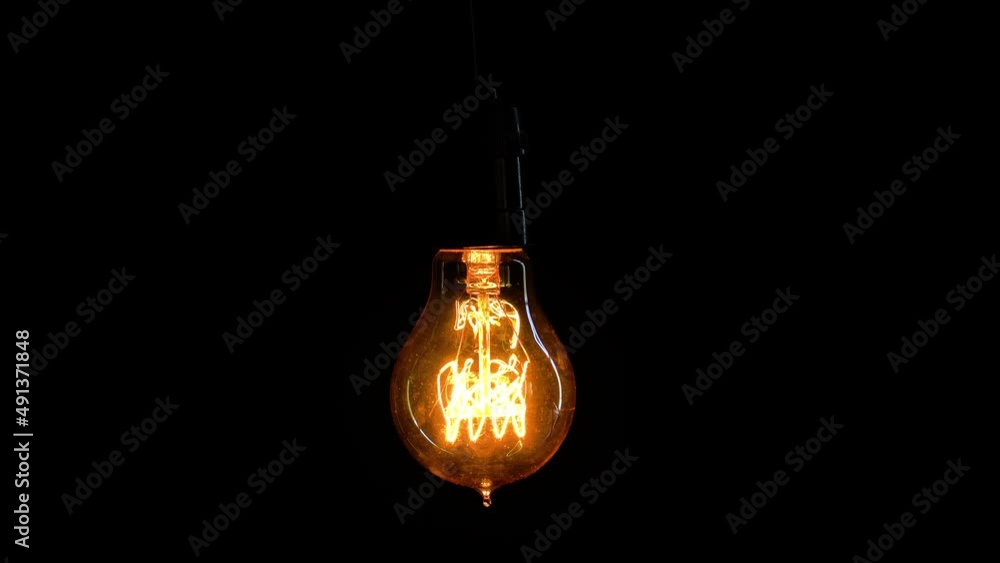Light bulb glowing on dark background in studio Light bulb glowing on dark background in studio
