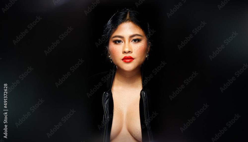 Asian 20s Woman chubby wear black fur jacket Red lips and freckles over black dark background Asian 20s Woman chubby wear black fur jacket Red lips and freckles over black dark background