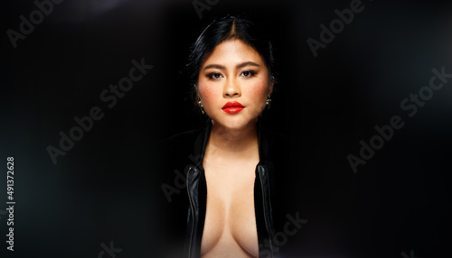 Asian 20s Woman chubby wear black fur jacket Red lips and freckles over black dark background