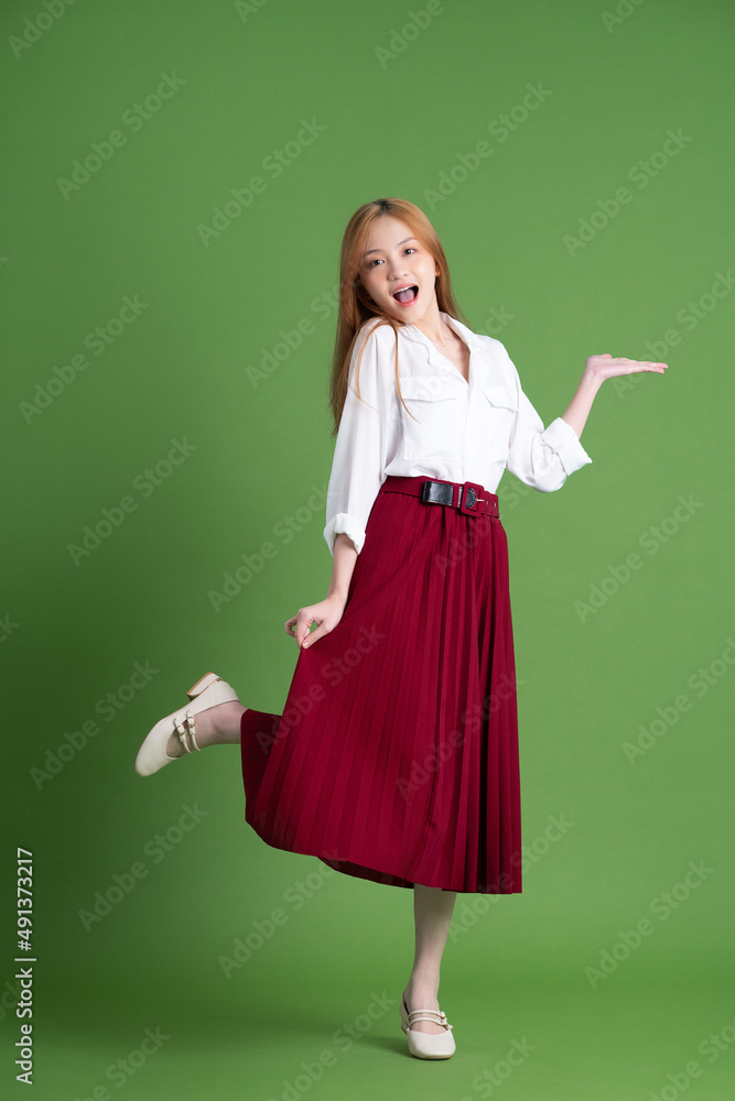 Beautiful young Asian woman dancing and posing on green background Beautiful young Asian woman dancing and posing on green background