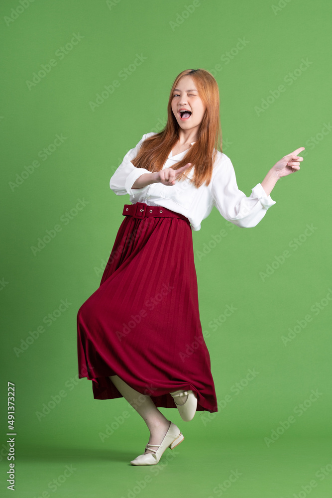 Beautiful young Asian woman dancing and posing on green background Beautiful young Asian woman dancing and posing on green background
