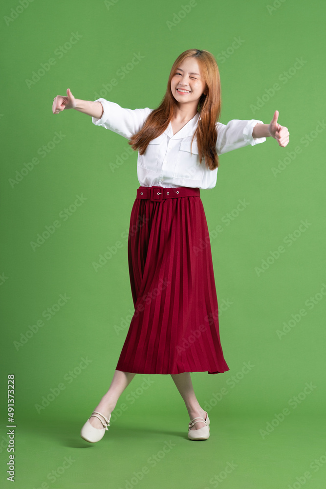 Beautiful young Asian woman dancing and posing on green background Beautiful young Asian woman dancing and posing on green background