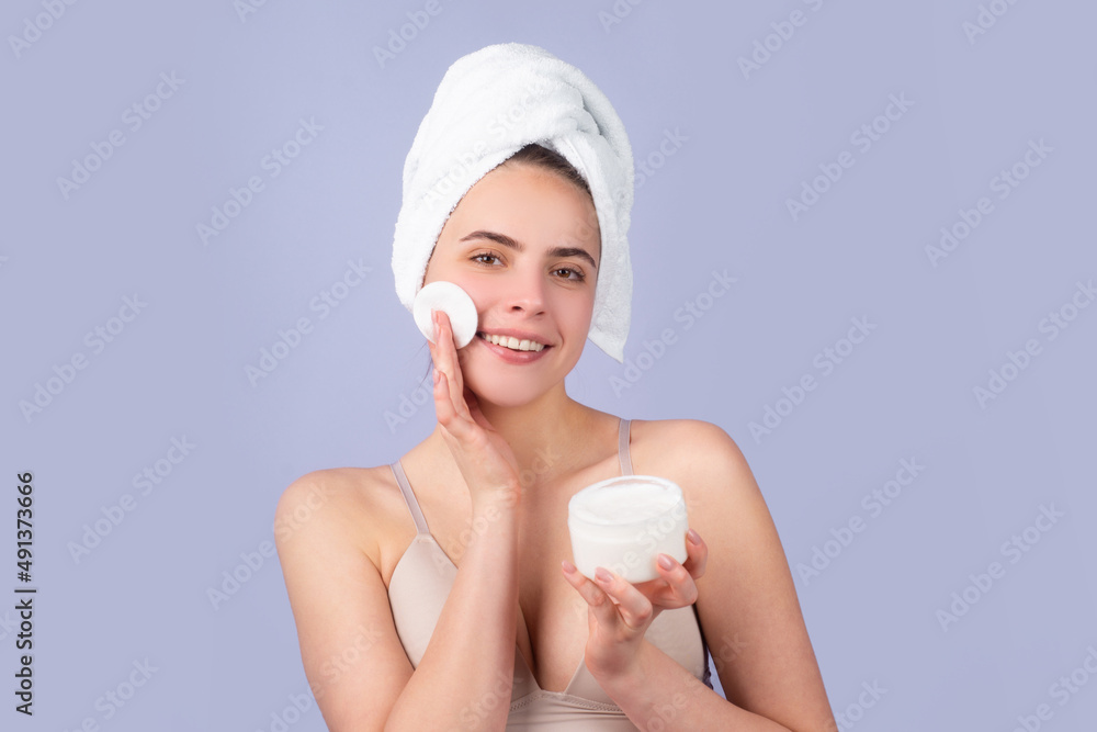 Cosmetic products. Woman with a facial mask. Charming pretty model after bath wrapped in towel applying using face mask, sensual face. Head shot beautiful woman applying moisturizer on skin. Cosmetic products. Woman with a facial mask. Charming pretty model after bath wrapped in towel applying using face mask, sensual face. Head shot beautiful woman applying moisturizer on skin.