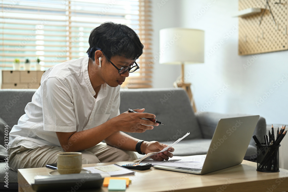Focused man calculating household expenses expenditures, make payment on laptop computer. Focused man calculating household expenses expenditures, make payment on laptop computer.
