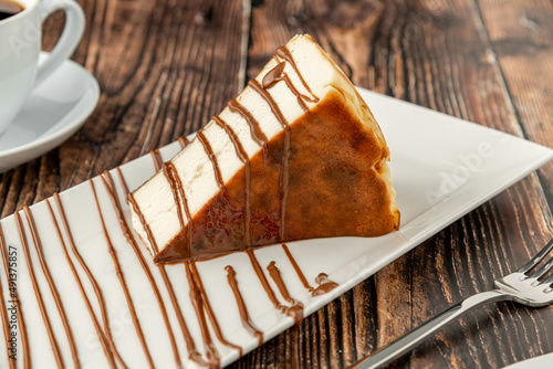 Sliced san sebastian cheesecake with coffee on wooden table photo