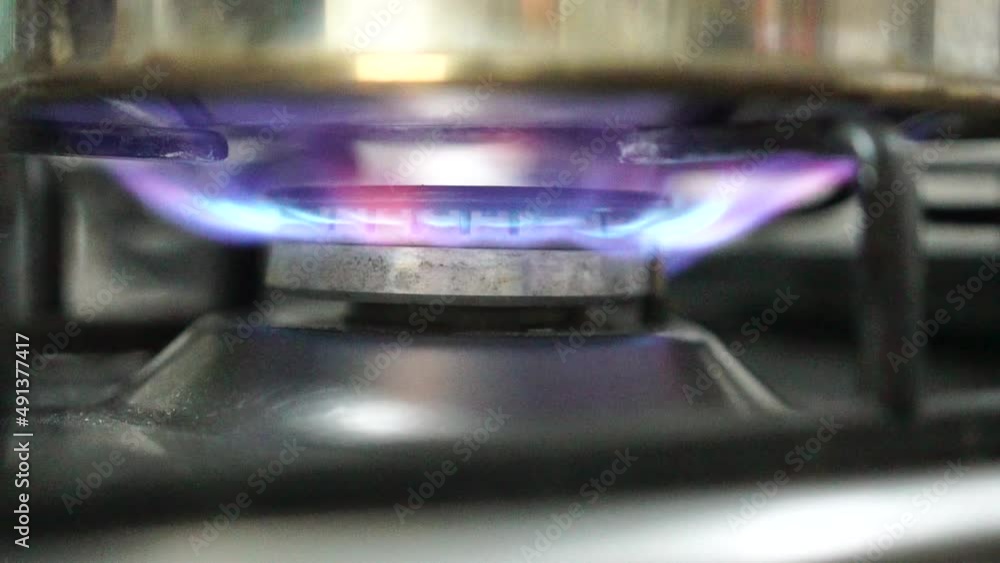 Unrecognizable woman hand turning on stove switch, lighting kitchen burner of gas stove indoors. Stove burner igniting into blue cooking flame. Natural gas inflammation. Close up, slow motion. Unrecognizable woman hand turning on stove switch, lighting kitchen burner of gas stove indoors. Stove burner igniting into blue cooking flame. Natural gas inflammation. Close up, slow motion.