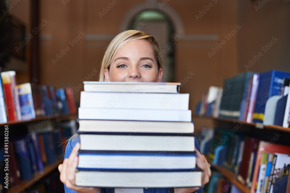 This is my study material for the semester. Portrait of a beautiful young student holding a large pile of textbooks.