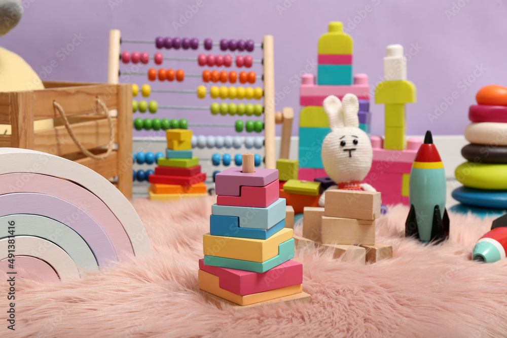 Fototapeta premium Set of different toys on rug near violet wall