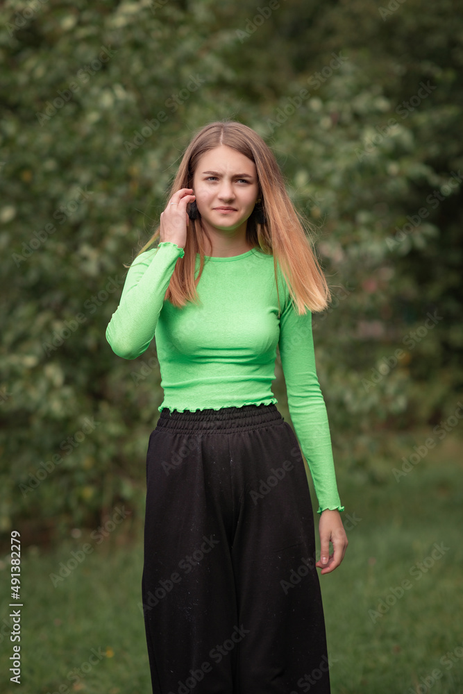 Portrait of a young beautiful girl in a green blouse in the park in summer. Portrait of a young beautiful girl in a green blouse in the park in summer.