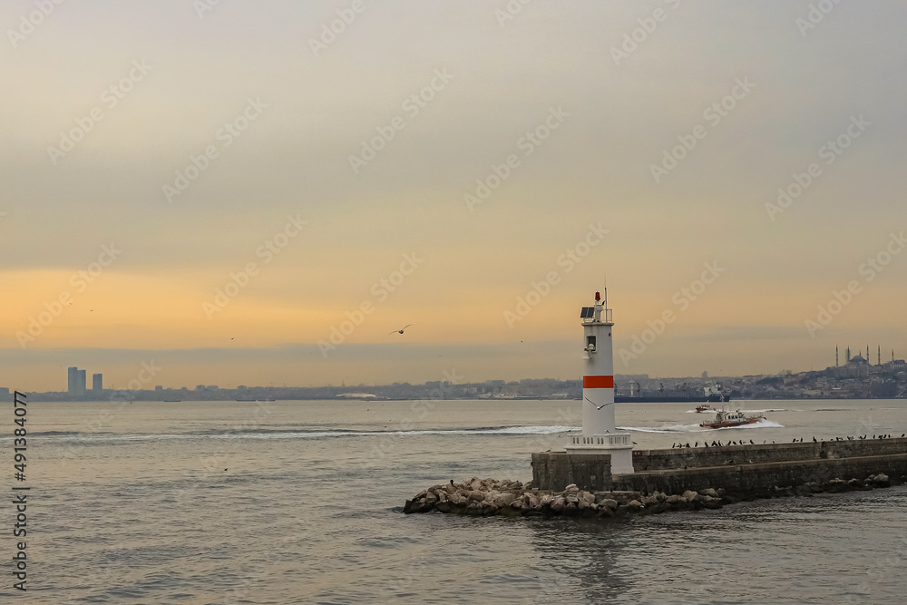 a small lighthouse and a sunset with beautiful colors behind it