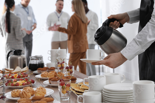 Obraz na płótnie Waitress pouring hot drink during coffee break, closeup