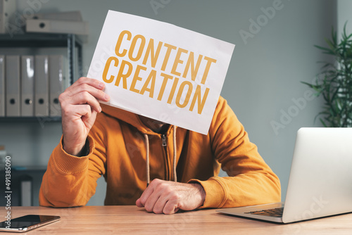 Fotografija Content creation, man holding paper in front of his face in home office interior
