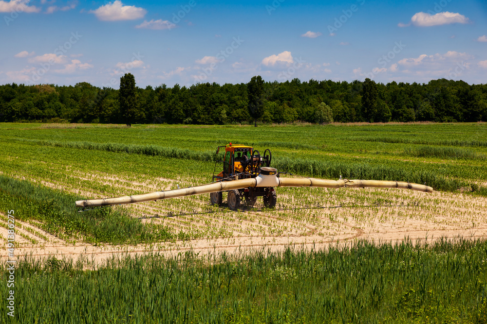 Fototapeta premium Tractor fertilize field Spraying pesticide and insecticide