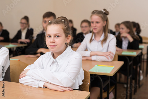 Happy schoolchildren sit at a desk in the classroom © Artem Zakharov