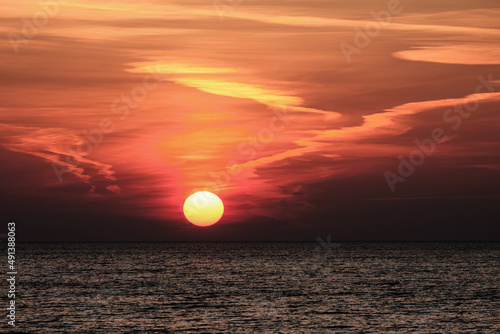 sun setting in the sea with cloud trails