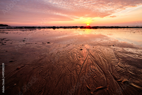 water trails in the beach sand at sunset