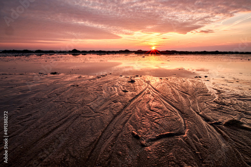 water trails in the beach sand at sunset