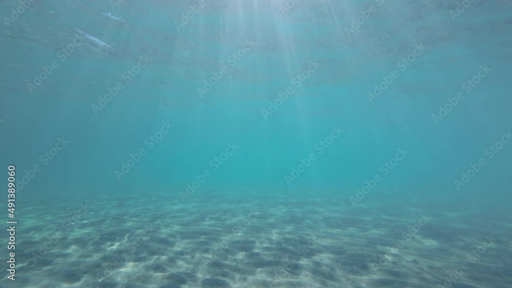 Slow motion, Sunrays penetrate through the surface of the water over sandy bottom. Underwater light creates a beautiful veil, consisting of sunlight. Sunset under surface of the water above seabed Slow motion, Sunrays penetrate through the surface of the water over sandy bottom. Underwater light creates a beautiful veil, consisting of sunlight. Sunset under surface of the water above seabed