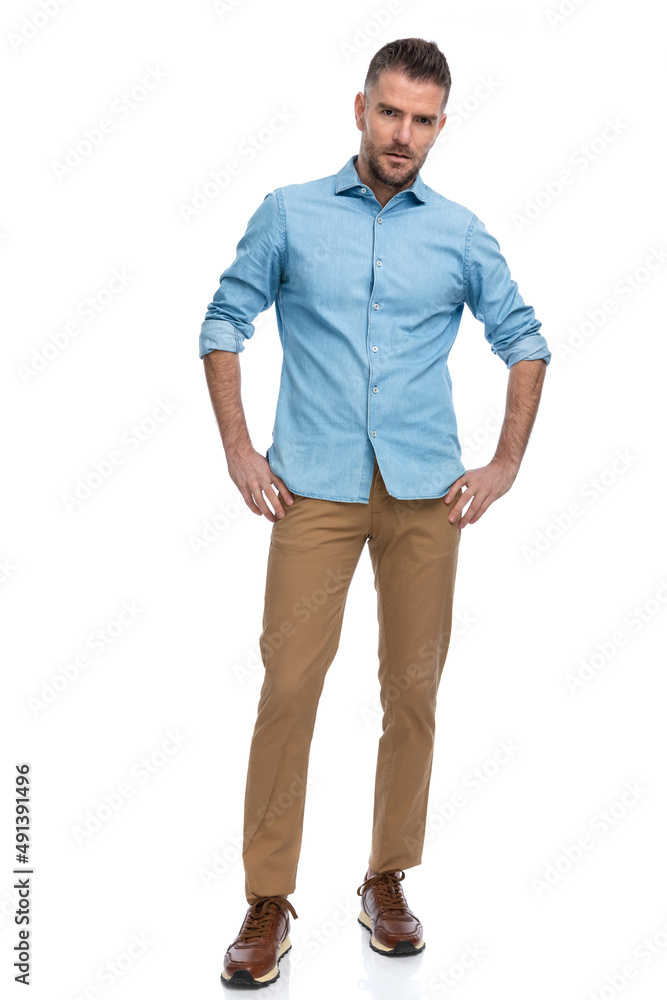 Fototapeta premium grizzled bearded man in blue denim shirt holding hands on hips