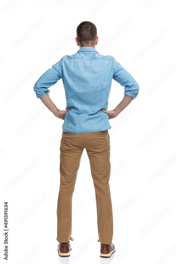 rear view of casual man with hands on hips standing rear view of casual man with hands on hips standing