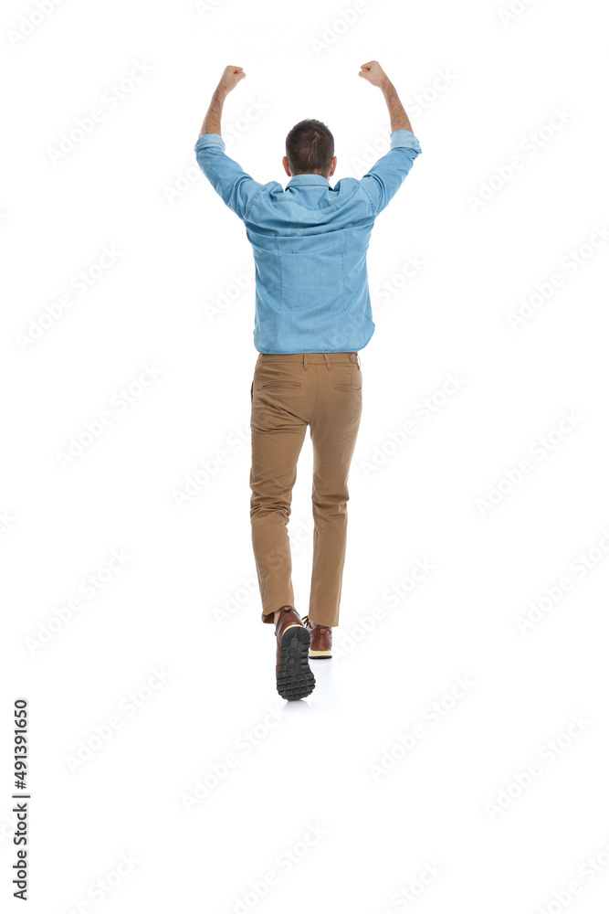 behind view of smart casual guy with blue jeans shirt holding fists up