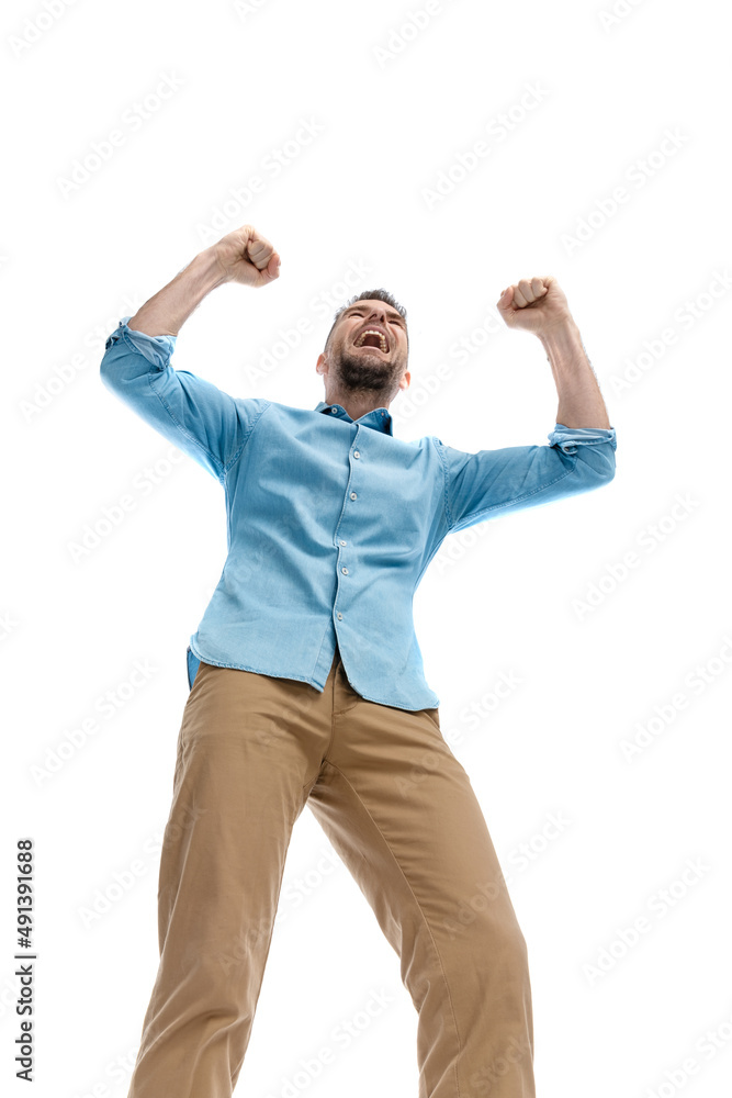 low angle surprising enthusiastic young guy with arms in the air low angle surprising enthusiastic young guy with arms in the air