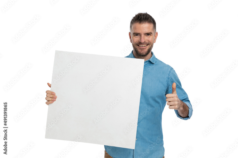 attractive young guy holding board and making thumbs up sign attractive young guy holding board and making thumbs up sign