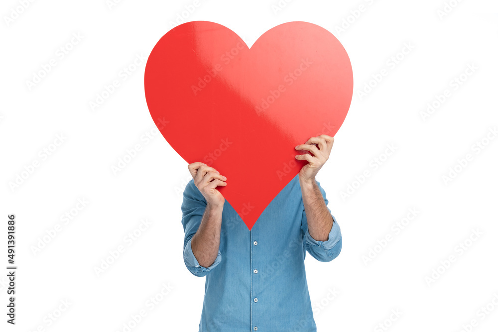 man in jeans shirt covering face with big red heart on valentine's day man in jeans shirt covering face with big red heart on valentine's day