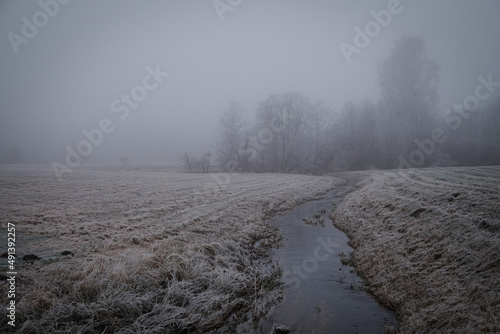 small river on a farming field on a misty cloudy winter day