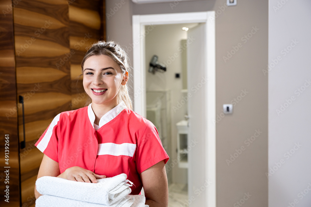Portrait of smiling maid with fresh towels in hotel room. Portrait of smiling maid with fresh towels in hotel room.