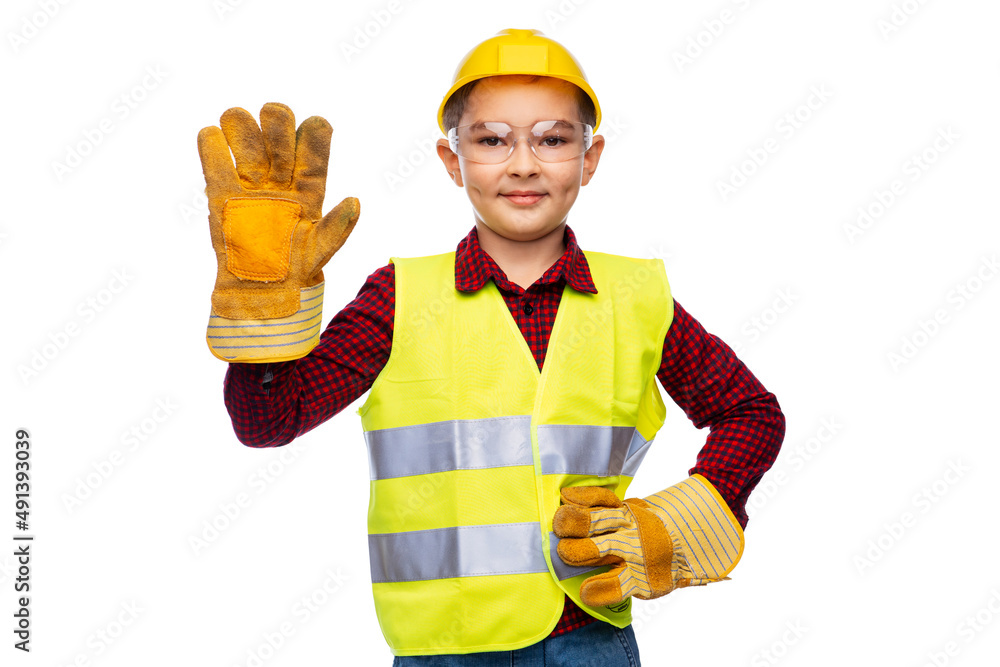 building, construction and profession concept - little boy in protective helmet, gloves, goggles and safety vest over white background building, construction and profession concept - little boy in protective helmet, gloves, goggles and safety vest over white background