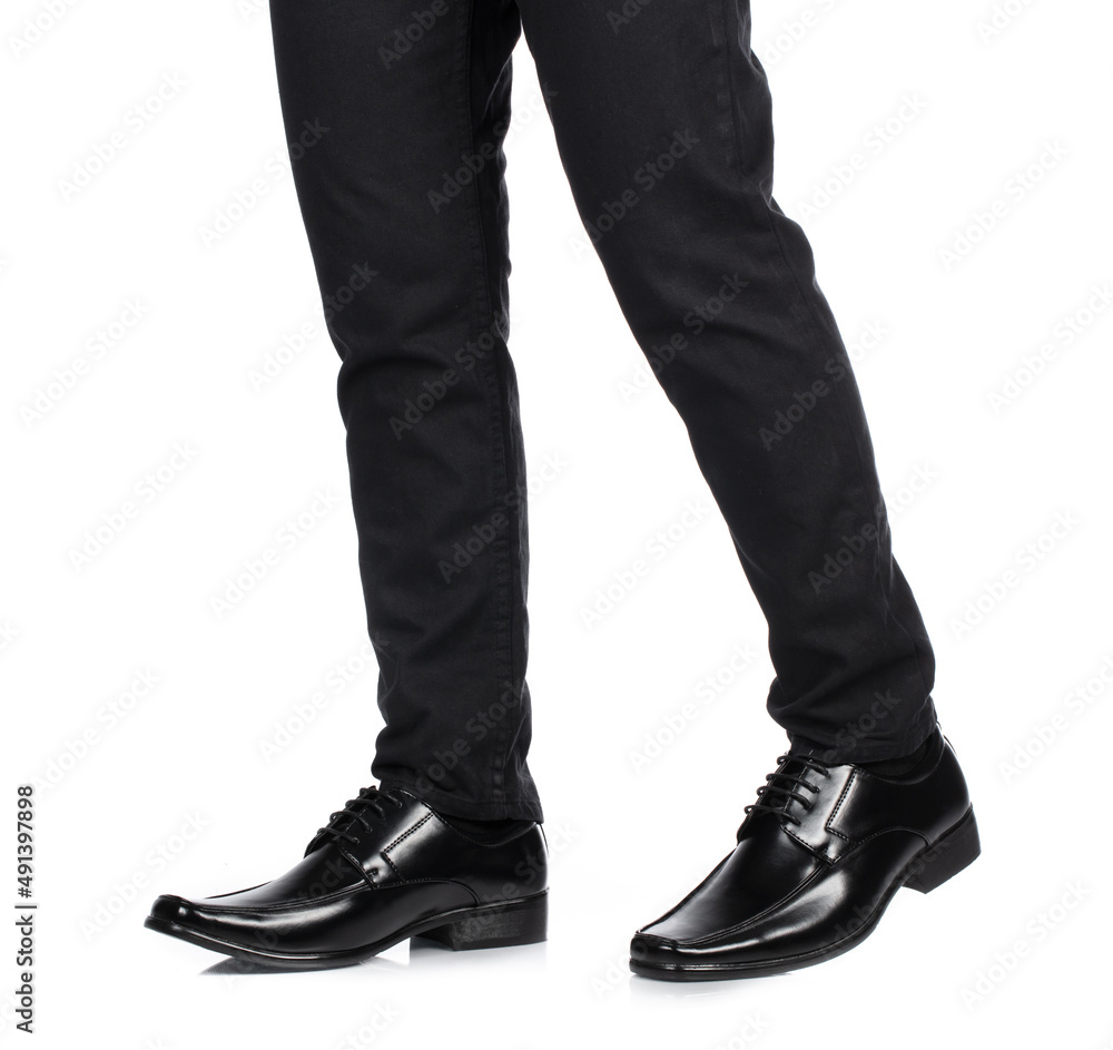 Man's feet in black trousers and black shoes isolated on white background