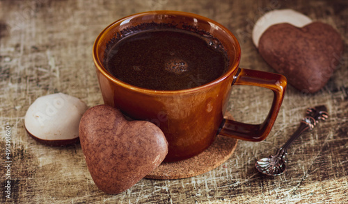 brown ceramic mug with black coffee and heart-shaped chocolate chip cookies
