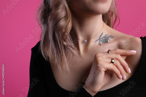 Beautiful woman with tattoo on body against pink background, closeup