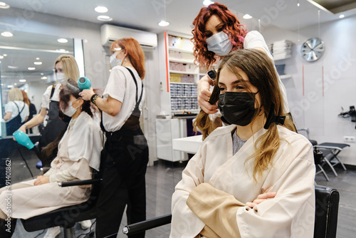 Young woman with a face mask getting a new hairstyle at the hair salon.