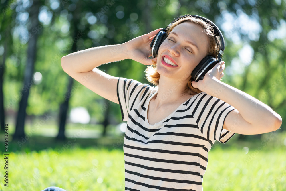 Young woman happens to have music in a summer park Young woman happens to have music in a summer park