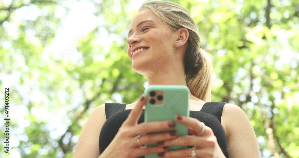 Young woman using a smartphone at day time with a green park. High quality video. Mobile phone, technology, urban concept. Young woman using a smartphone at day time with a green park. High quality video. Mobile phone, technology, urban concept.