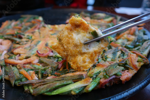 It is a Korean pancake made of seafood and green onions. photo